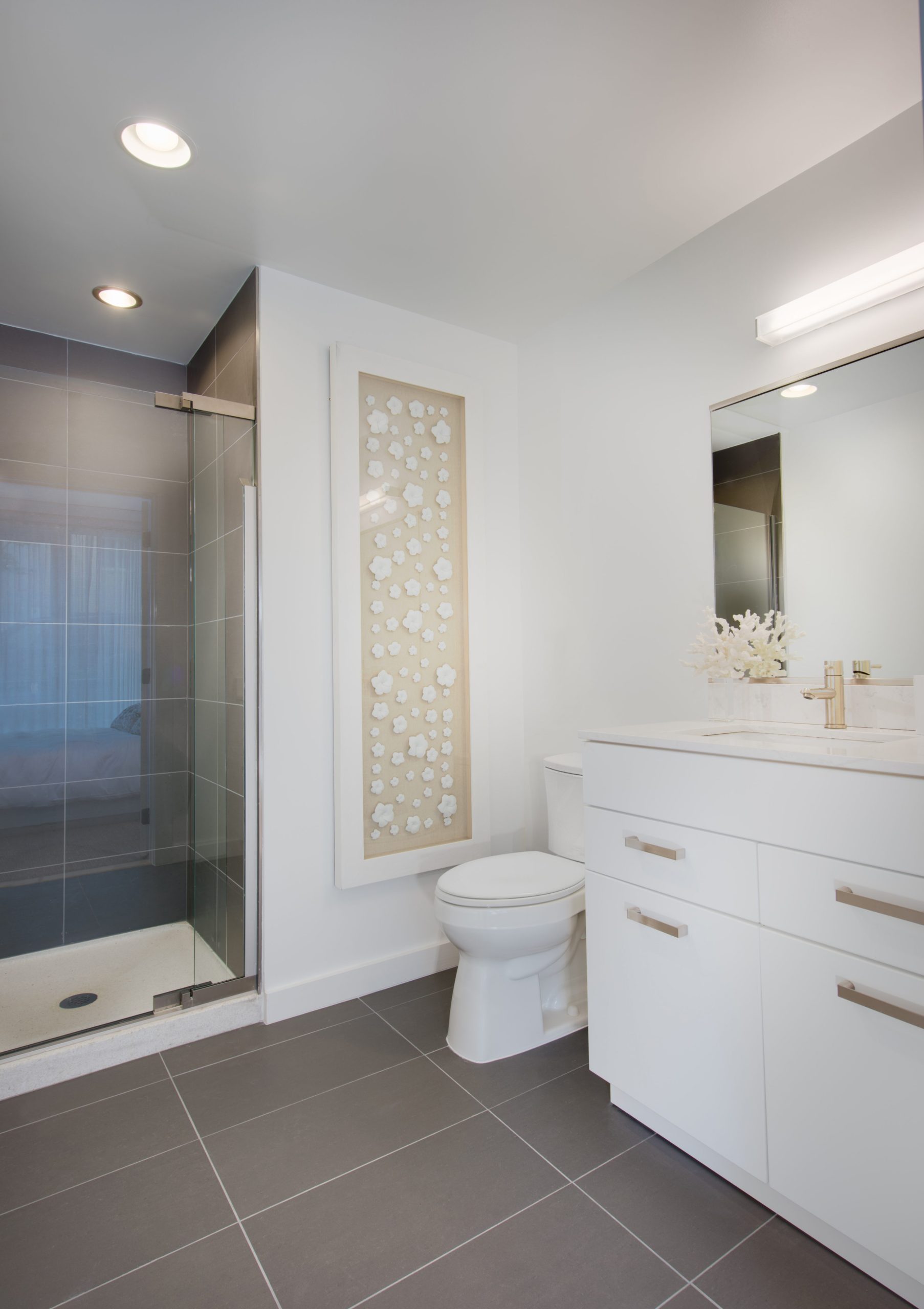 Model apartment bathroom at Fifty Three Thirty Three Apartments with glass shower, white vanity, and modern tile.