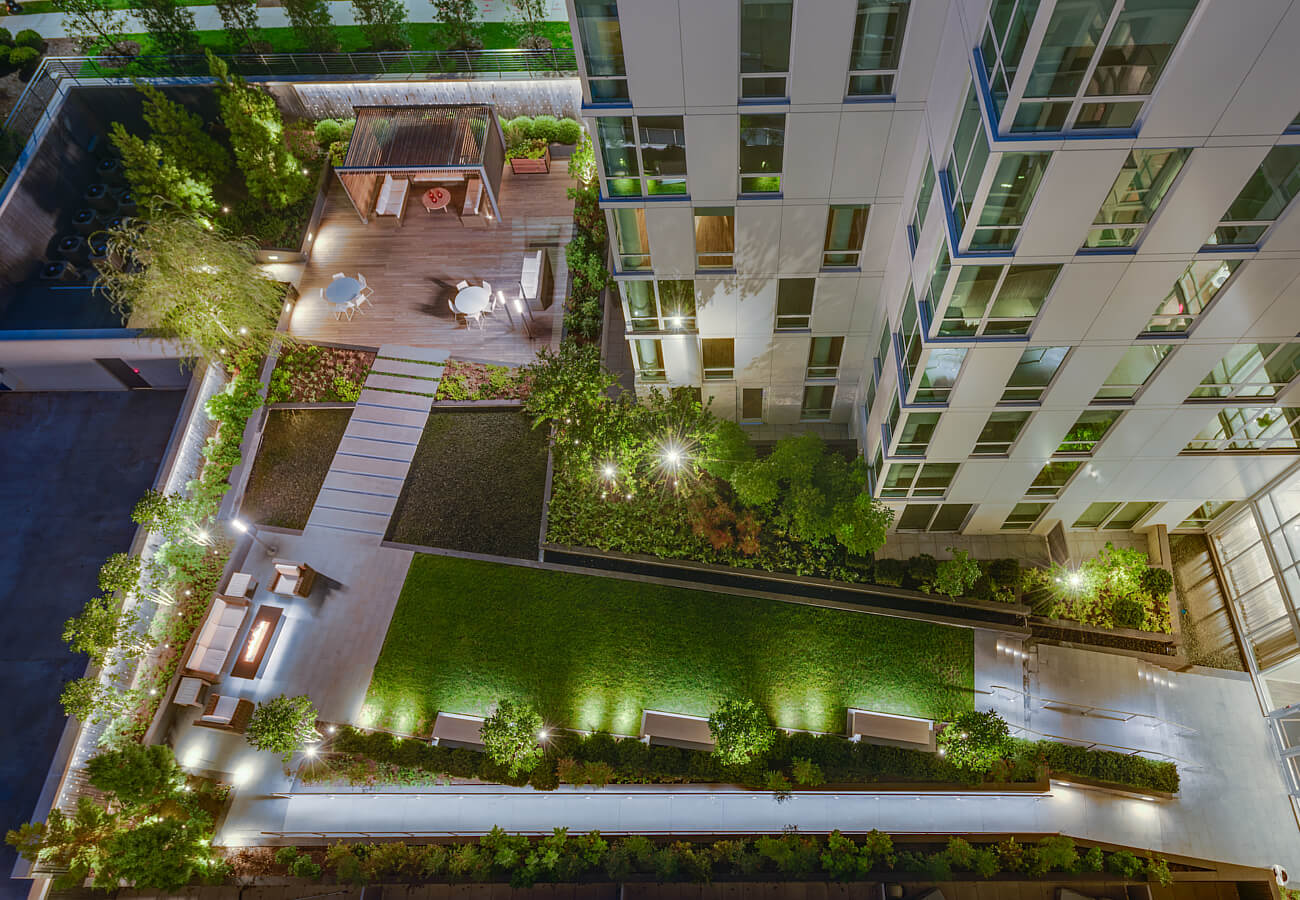 Overhead nighttime view of the landscaped courtyard at Fifty Three Thirty Three Apartments with seating, pathways, and lighting.