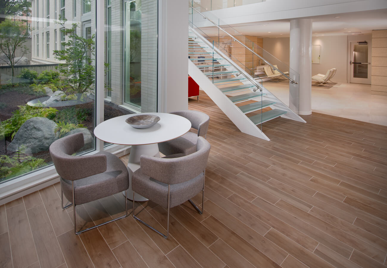Tall lobby view at Fifty Three Thirty Three Apartments with glass staircase, pendant lights, and floor-to-ceiling windows.