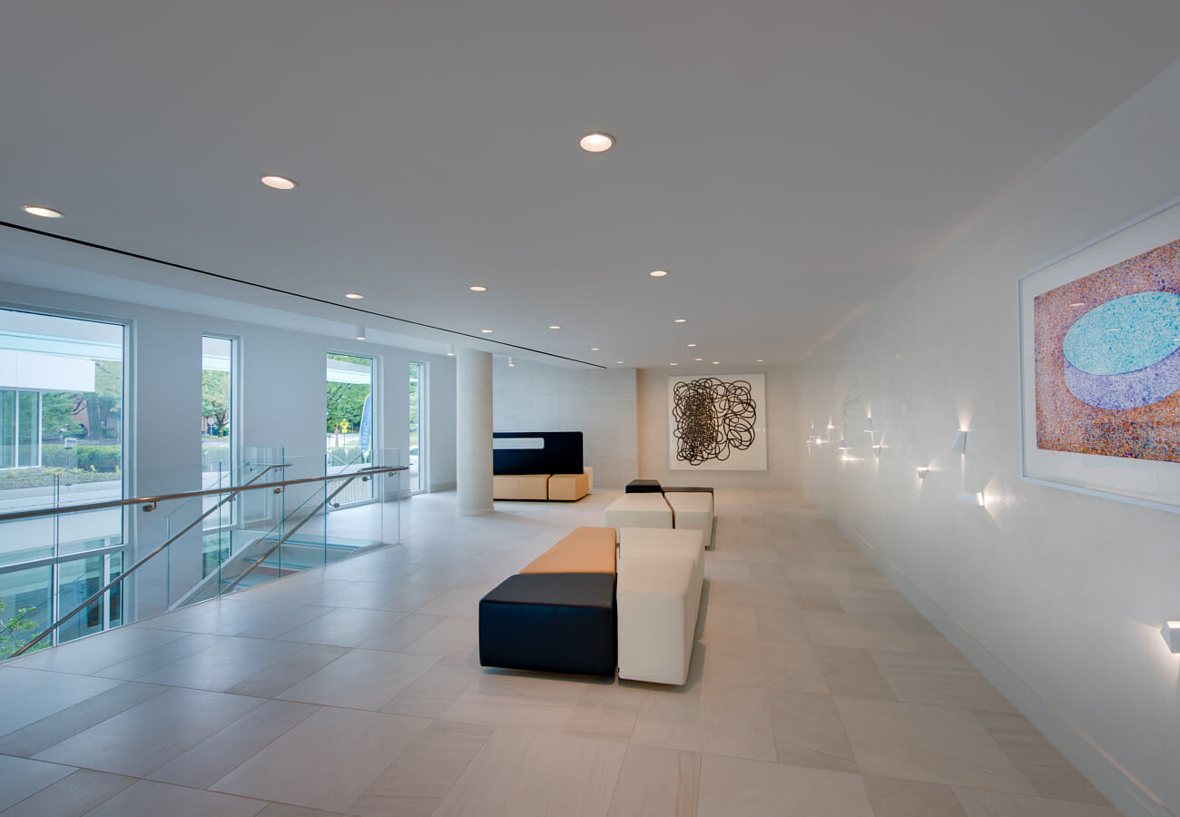 Lobby seating area at Fifty Three Thirty Three Apartments with modern benches, wall art, and glass stair railing