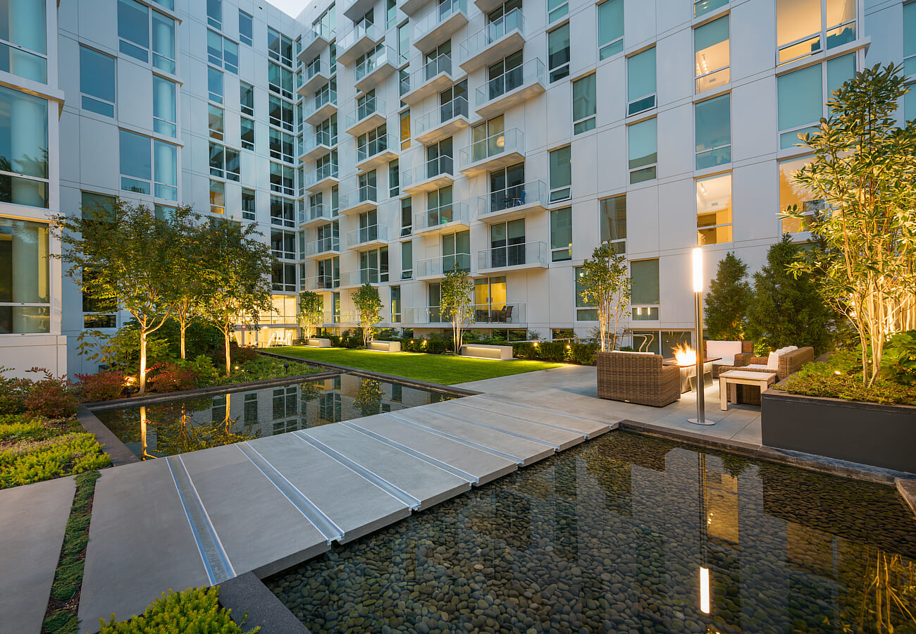 Courtyard at Fifty Three Thirty Three Apartments at night with reflecting pool, greenery, seating, and apartment balconies