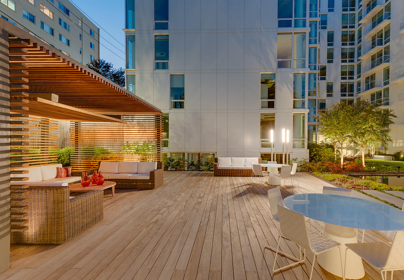 Nighttime courtyard seating area at Fifty Three Thirty Three Apartments with outdoor sofas, tables, and landscaped deck