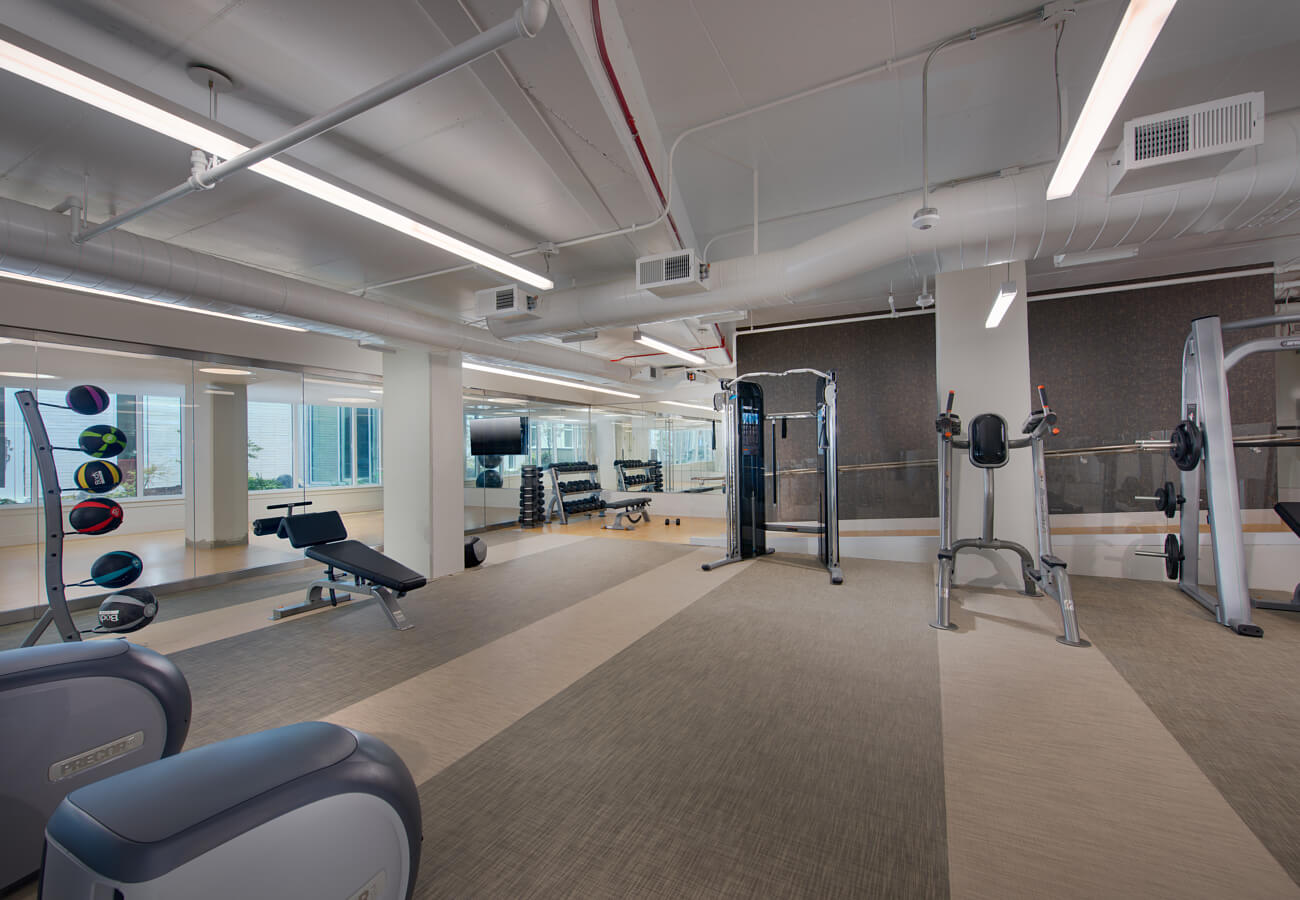 Fitness center at Fifty Three Thirty Three Apartments with free weights, strength machines, mirrors, and medicine balls