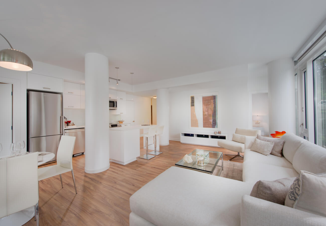 Model apartment open living and kitchen area at Fifty Three Thirty Three Apartments with sectional sofa and dining nook.