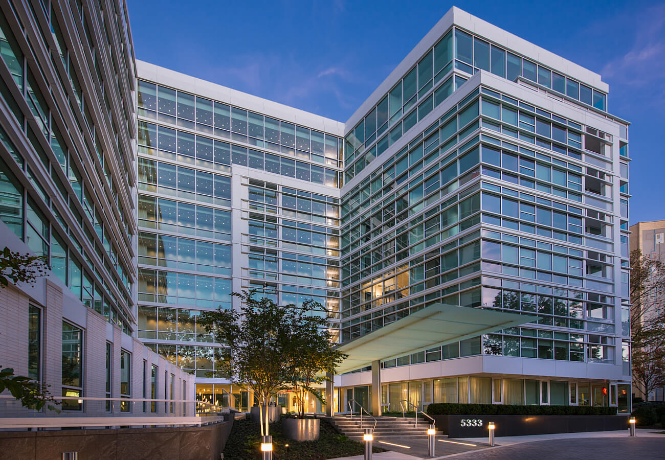 Nighttime exterior view of Fifty Three Thirty Three Apartments with glass facade, lit windows, and entrance canopy.