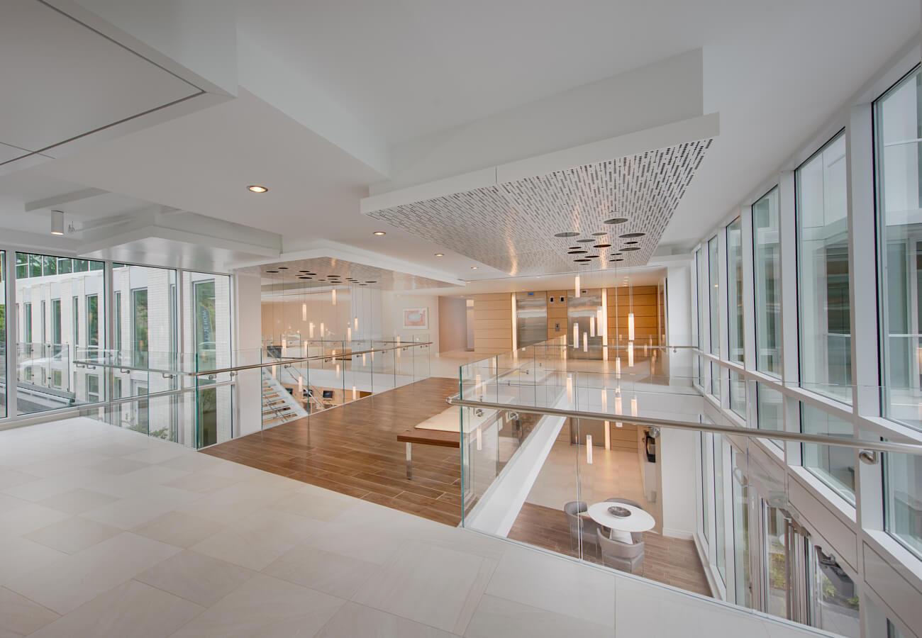 Upper lobby at Fifty Three Thirty Three Apartments with glass railings, large windows, elevators, and pendant lighting.