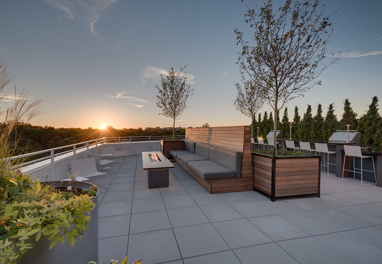 Rooftop terrace at Fifty Three Thirty Three Apartments with lounge seating, fire table, grills, and sunset views